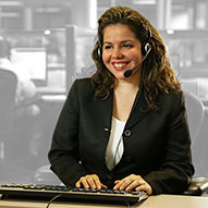 A support operator wearing a headset working on her computer helping a customer.