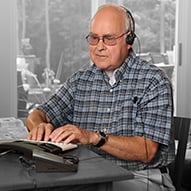 An elderly man using Hearing Carry Over equipment.
