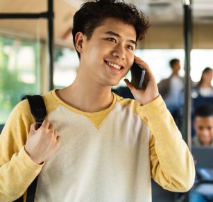A young Asian American male using a smartphone to talk with someone.