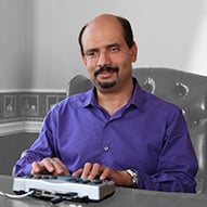An adult male in a purple shirt using Telebraille equipment to communicate.